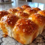 A cluster of freshly baked Hot Honey Garlic Dinner Rolls, glistening with a sticky glaze and sprinkled with red pepper flakes.