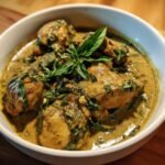 Close-up of Irresistible Coconut Basil Chicken Curry, featuring chicken pieces in a creamy green sauce, garnished with fresh basil.