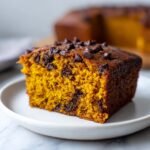 Close-up of a moist slice of Irresistible Pumpkin Chocolate Cake studded with chocolate chips.