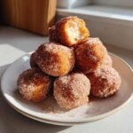 A stack of golden brown, sugar-coated Irresistible Tasty Angel Cake Churro Bites on a small white plate.