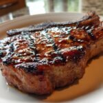 Close-up of a thick, juicy pork chop coated in glossy Jerk Sauce Grilled Pork Chops glaze, showing distinct grill marks.