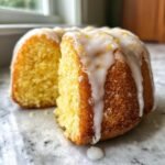 Close-up of a slice cut from a Lemon Ginger Bundt Cake, featuring a thick white glaze and lemon zest topping.