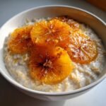 A close-up of creamy Maple Cinnamon Oatmeal topped with glistening, caramelized orange slices.