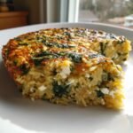 A close-up slice of Orzo Frittata With Spinach And Feta showing pasta, green spinach, and white feta cheese.