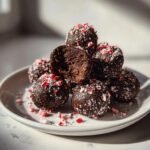 A stack of dark chocolate Peppermint Raspberry Chocolate Oreo Cookie Balls rolled in crushed candy canes.