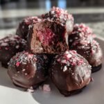 Stack of Peppermint Raspberry Chocolate Oreo Cookie Balls dipped in chocolate and topped with crushed candy canes.