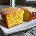 Two moist slices of bright yellow Perfect One Bowl Lemon Birthday Sheet Cake with white glaze and zest.