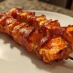 Close-up of two skewers featuring perfectly cooked Prosciutto Wrapped Salmon Skewers, glistening and slightly charred.