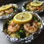 Close-up of cooked Shrimp Foil Packets With Broccoli Rice, topped with a lemon slice.