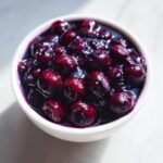 A close-up view of rich, dark Simple Blueberry Compote served in a small white bowl.