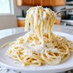 A fork lifts spaghetti coated in creamy, cheesy Easy Garlic Parmesan Sauce, showing long cheese pulls.