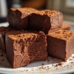 Close-up of rich, dark chocolate fudge squares dusted with cocoa powder, showcasing the texture of the Spicy Mexican Hot Chocolate Fudge.