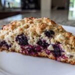 Close-up of a freshly baked Blackberry White Chocolate Oatmeal Scones slice on a white plate.
