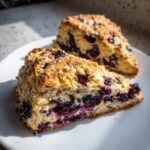 Two slices of Blackberry White Chocolate Oatmeal Scones showing a rich filling of dark berries and white chocolate chunks.