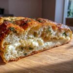 Cross-section of a warm, cheesy slice of Irresistible Copycat Subway Italian Herb Cheese Bread showing melted cheese filling and herbs.