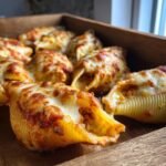 Close-up of baked conchiglioni pasta shells stuffed and topped with melted cheese, part of the Creamy Garlic Tomato Conchiglioni Pasta dish.