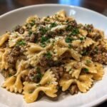 Close-up of Irresistible Creamy Parmesan Garlic Beef Bowtie Pasta topped with parsley and cheese.
