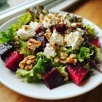 A vibrant plate featuring a Delightful Beet And Goat Cheese Salad with mixed greens, cubed beets, crumbled goat cheese, and walnuts.