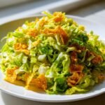 A mound of shredded lettuce topped with crunchy Fritos for a Flavorful Frito Cowboy Cabbage.