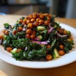 A vibrant mound of Healthy Loaded Kale Salad topped generously with spicy chickpeas, red onion, and cucumber.