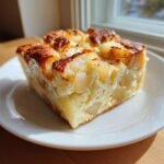 A square serving of Heavenly Cardamom Pear Bread Pudding Recipe Delight, showing soft custard and baked pear chunks.