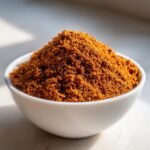 A close-up of a mound of rich, reddish-brown Homemade Jerk Dry Rub Seasoning in a small white bowl.