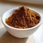 A close-up of a small white bowl filled high with rich brown Homemade Pumpkin Pie Spice Blend.