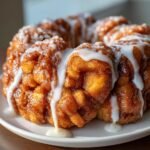 Close-up of Irresistible Apple Fritter Monkey Bread, sticky and golden brown, topped with thick white icing drizzle.