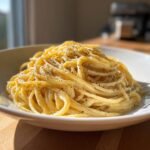 A close-up of a bowl of Irresistible Cacio E Pepe pasta, coated in creamy sauce and topped with coarse black pepper.