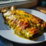 Close-up of two Irresistible Delicious Green Chicken Enchiladas smothered in melted, browned cheese and green sauce.