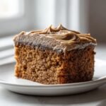 A close-up of a moist slice of Irresistible Gingerbread Cake topped with swirled cinnamon molasses frosting.