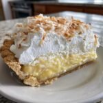 A thick slice of Irresistible Homemade Coconut Cream Pie Delight with creamy filling and toasted coconut topping.