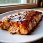 A flaky, cooked salmon fillet generously coated in a glossy, dark honey mustard glaze, ready for an Irresistible Honey Mustard Salmon Recipe.