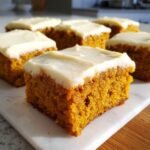 Close-up of a square slice of Irresistible Old Fashioned Pumpkin Bars topped with thick cream cheese frosting.