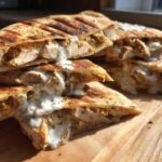 Cross-section of grilled Irresistible Sheet Pan Chicken Pitas stuffed with seasoned chicken and dripping with herby ranch sauce.