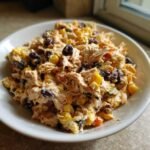 A close-up view of a bowl filled with creamy, shredded Irresistible Southwest Chicken Salad featuring corn and black beans.