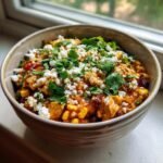 A close-up of a bowl filled with Irresistible Street Corn Chicken Chili, topped with cotija cheese and fresh cilantro.
