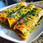 Three baked Irresistible Vegan Enchiladas Verdes covered in melted vegan cheese and fresh cilantro.
