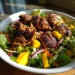 Close-up of Oven Baked Jamaican Jerk Chicken Salad with chunks of seasoned chicken, mango, and red onion over lettuce.