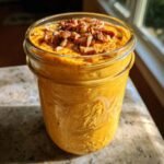 Close-up of Pumpkin Spice Overnight Oats in a mason jar, topped with chopped pecans and cinnamon.