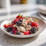 A close-up of the Refreshing Berry Chicken Salad, featuring chunks of chicken mixed with poppy seeds and topped with fresh strawberries, raspberries, blueberries, and blackberries.
