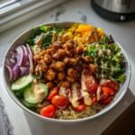 A vibrant Savory Chickpea Quinoa Buddha Bowl topped with crispy chickpeas, fresh vegetables, and creamy dressing.