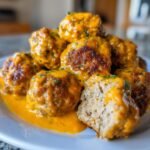 Close-up of Savory Turkey Meatballs In Pumpkin Sage Sauce, showing texture and rich orange sauce.