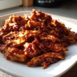 Close-up of shredded chicken coated in a thick, glossy sauce for the Irresistible Slow Cooker Honey Garlic Chicken Recipe.