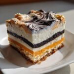 A layered slice of Spooktacular Halloween Lush Recipe showing orange, white, and dark chocolate layers on a white plate.