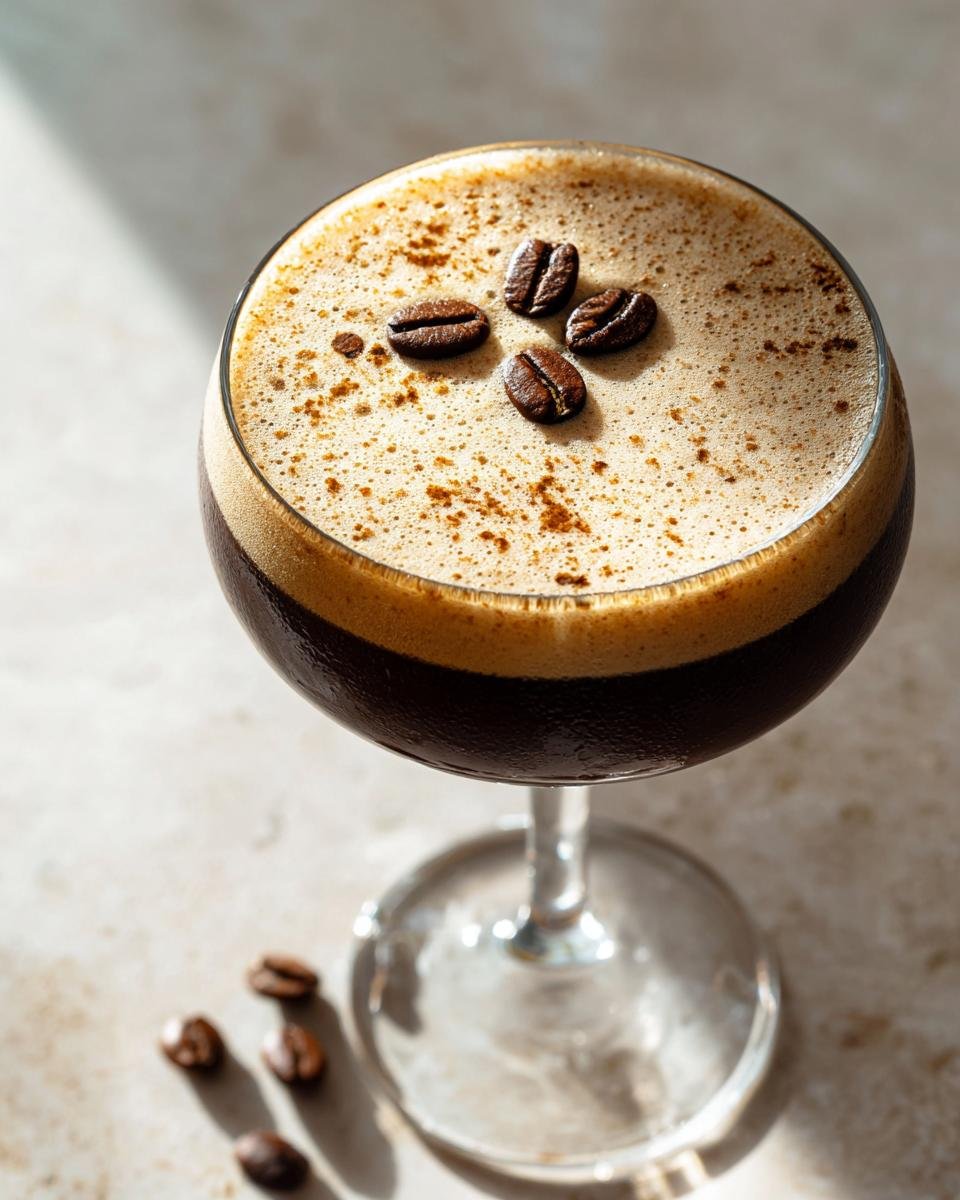 Close-up of a Vegan Espresso Martini Mocktail with thick foam, garnished with three coffee beans.