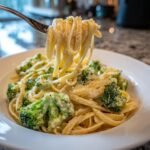 A fork lifting creamy linguine pasta coated in ricotta sauce with bright green broccoli florets, part of Zesty Lemon Ricotta Pasta.