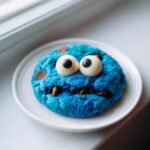 A single, vibrant blue Cookie Monster cookie with large candy eyes and chocolate chips for a mouth.