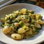 Close-up of Creamy Butter Beans With Leeks Lemon garnished with fresh parsley in a white bowl.