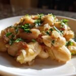 A close-up of Creamy Butter Beans With Leeks Lemon garnished with fresh parsley on a white plate.